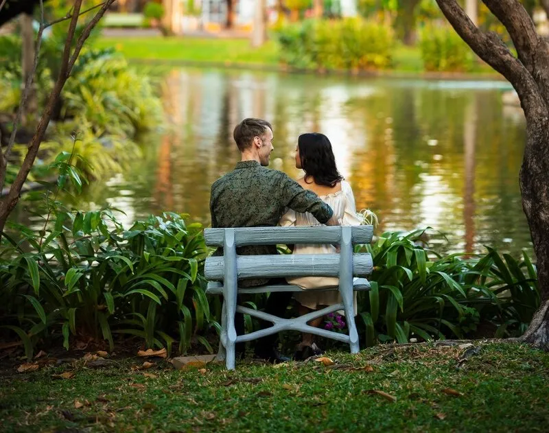 Couple sitting on bench by pond